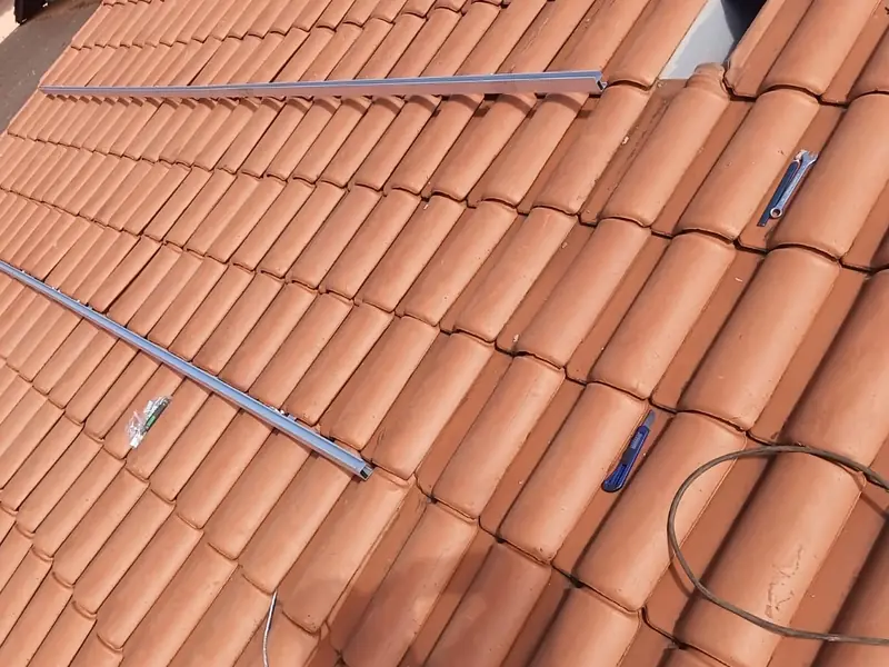 Trilhos de fixação instalados sobre telhado cerâmico, com ferramentas ao lado